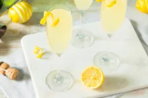 A glass of sparkling French 75 cocktail with a lemon twist garnish.